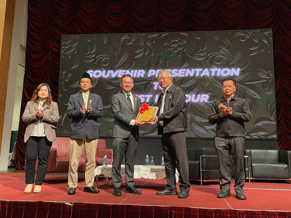 Ting (second right) gives a memento to Tiang as Bujang (second left) and others look on.