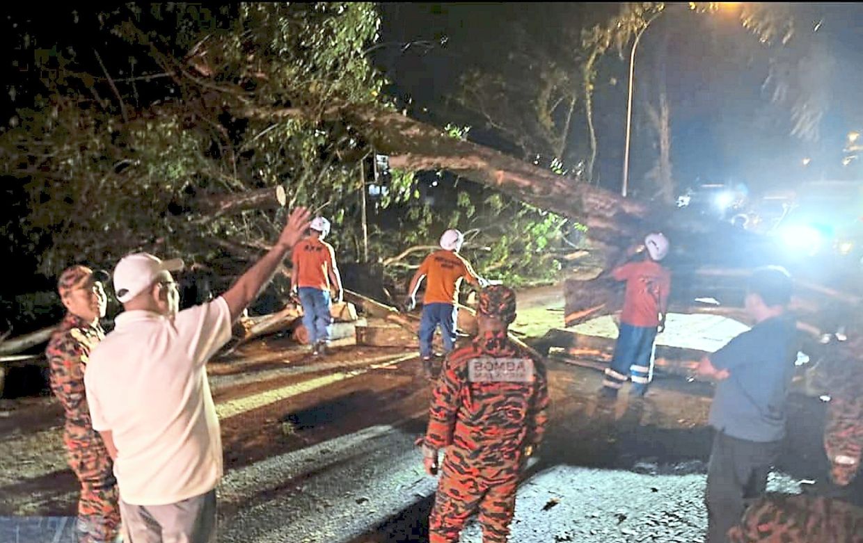 Firefighters clearing debris in Jalan Pahlawan after the freak storm.