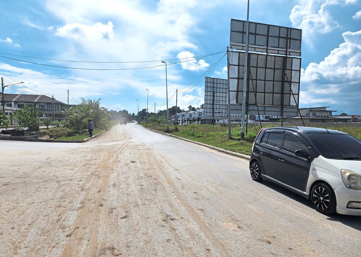 Jalan Bukit Penyau in Sibu is covered in dried mud from lorries entering and exiting construction areas.