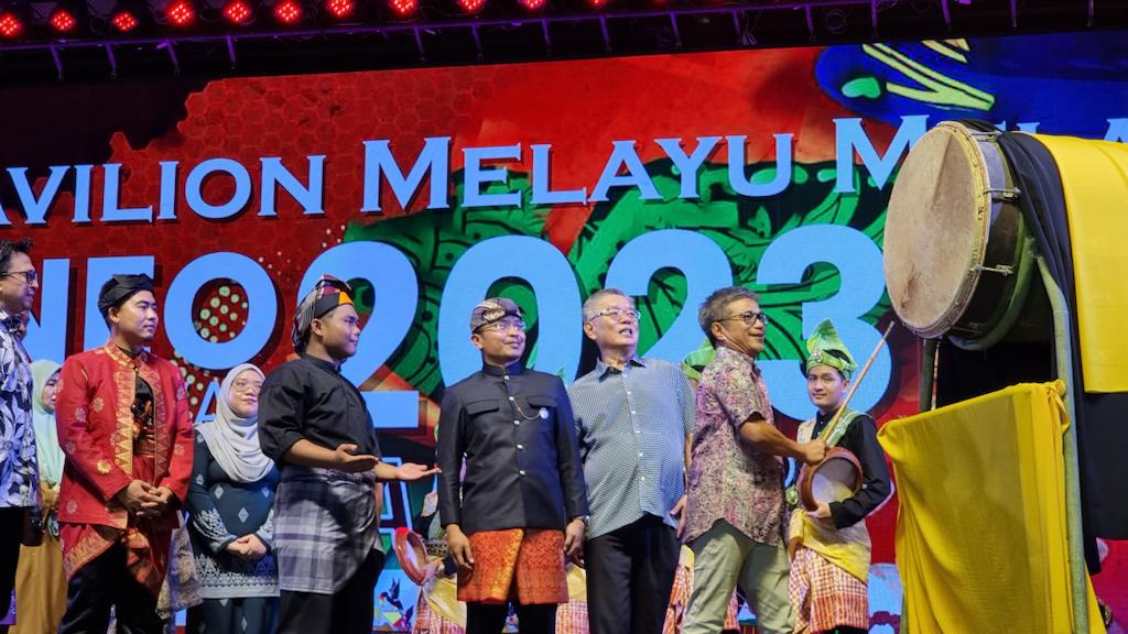 Dr Annuar hits a drum to launch the Malay Melanau Pavilion. From second right are Ting and Izkandar.