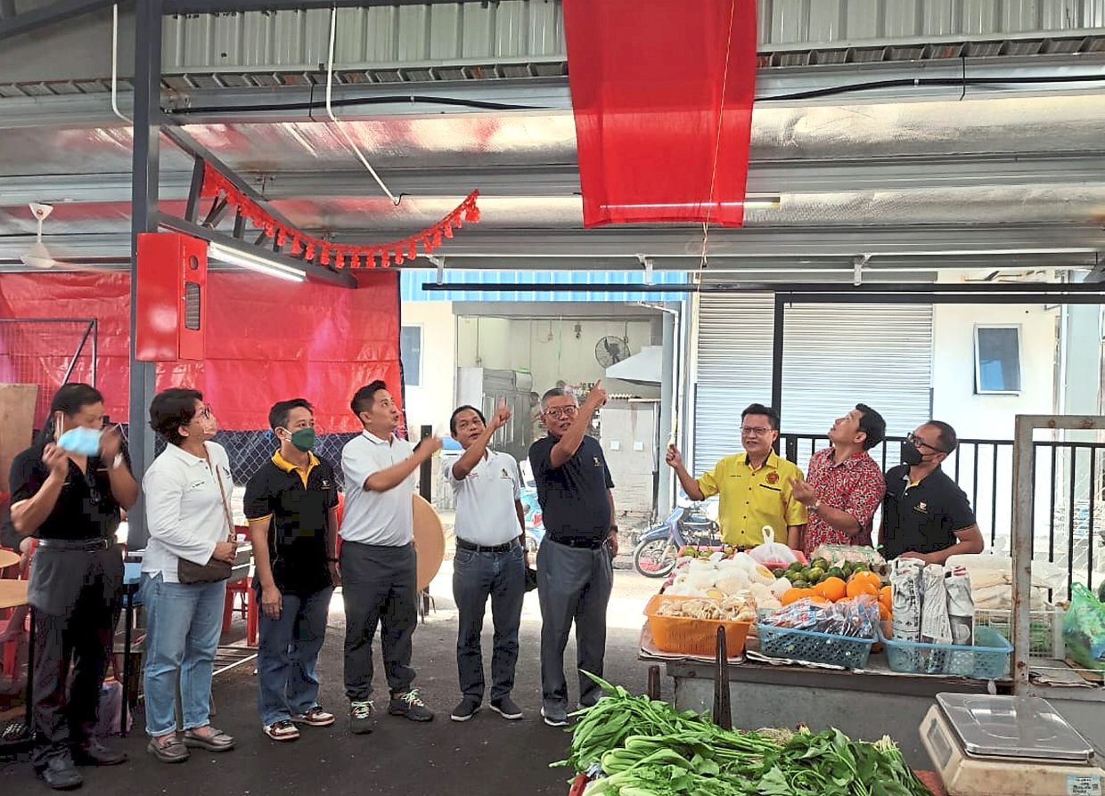 Chieng (third from right) and Ting (sixth from left) symbolically hanging up a signboard to open Tiong Hua Road Market.