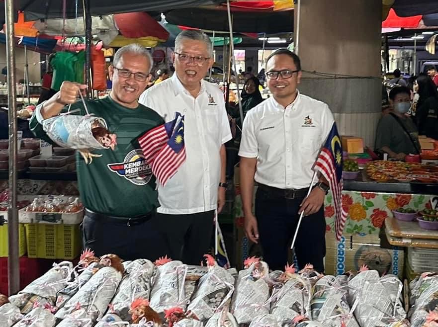 Helmy, Ting and Izkandar in a grop photo with Sibu unique ‘Chicken wrapped with old newspaper’. (Photo credit: Mohammed Abdullah Izkandar Roseley facebook)