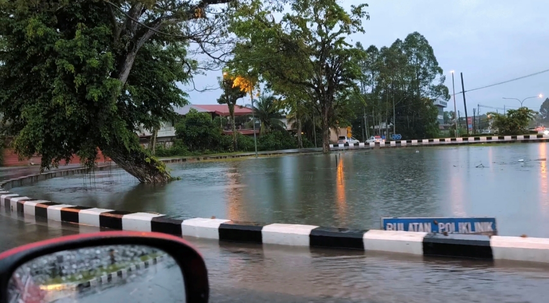 The roundabout turning into a pool with the road signage partially submerged in water. – Photo by Peter Boon