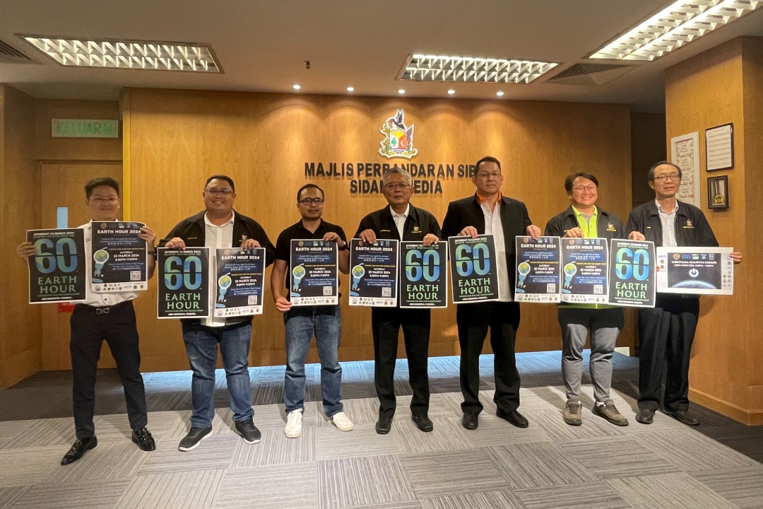 (From third left) Izkandar and Ting, joined by others, show the Earth Hour 2024 posters.