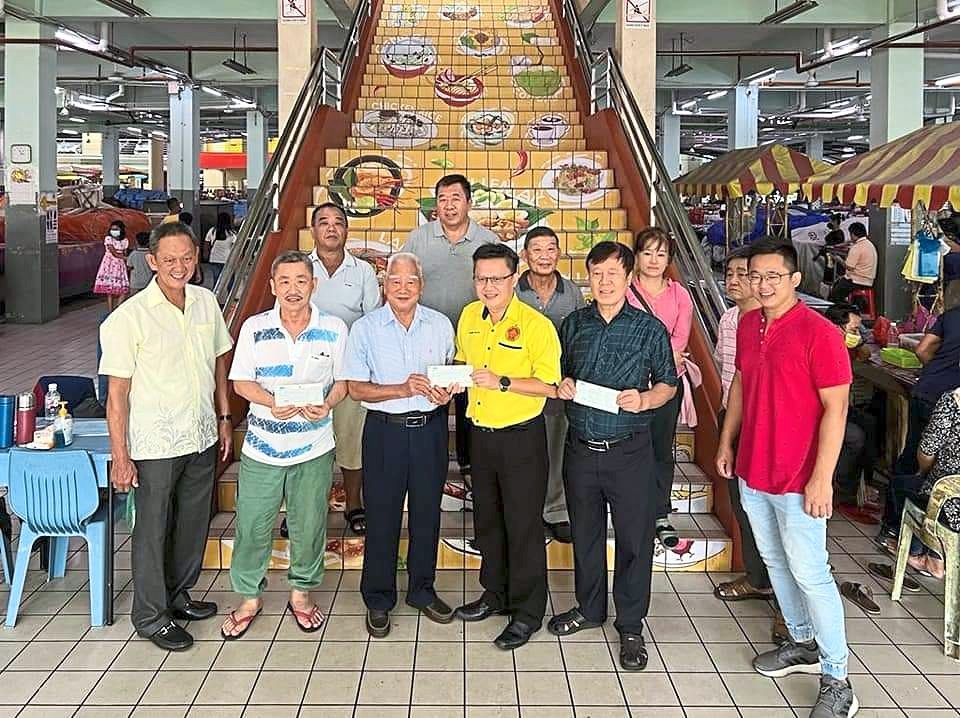Chieng (yellow shirt) presenting cheques to representatives of the three hawker associations.