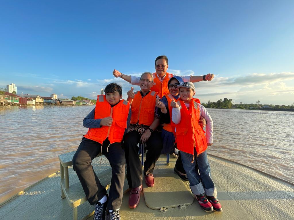 Raden and his family members are seen with Tieng (standing) during the river cruise.