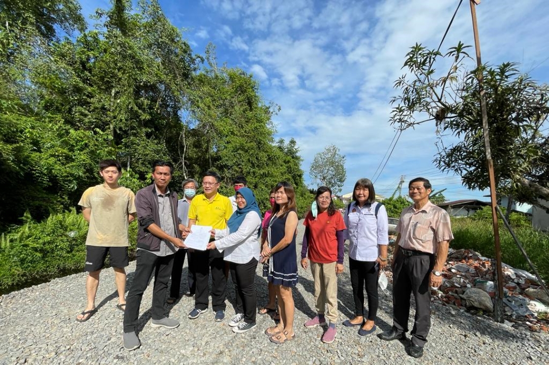 SMC assistant engineer Hussin Onn (second left) hands over the project to a representative of the contractor while Chieng (front third left) and the residents look on.