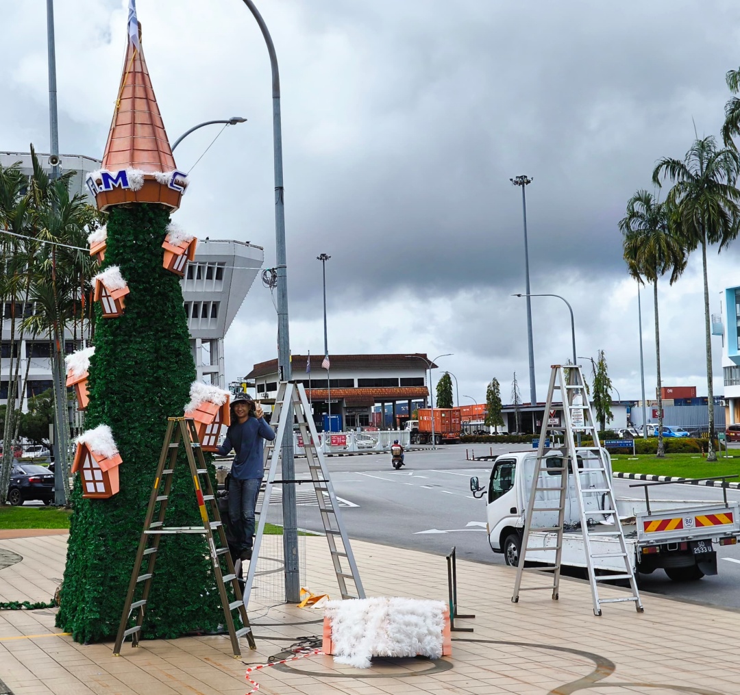 A worker putting up one of the entries for the festival pauses to pose for the camera. – Photo by Peter Boon