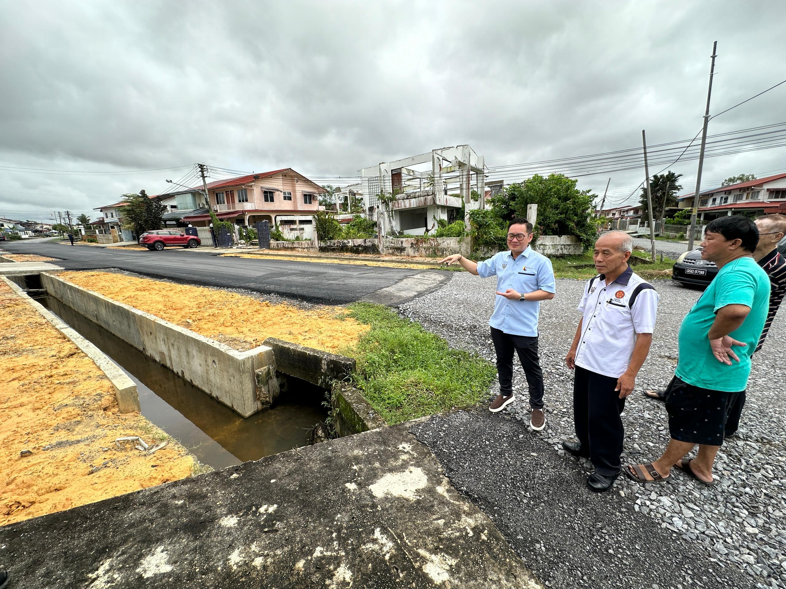Tiang (left) inspects the upgraded drain and road.